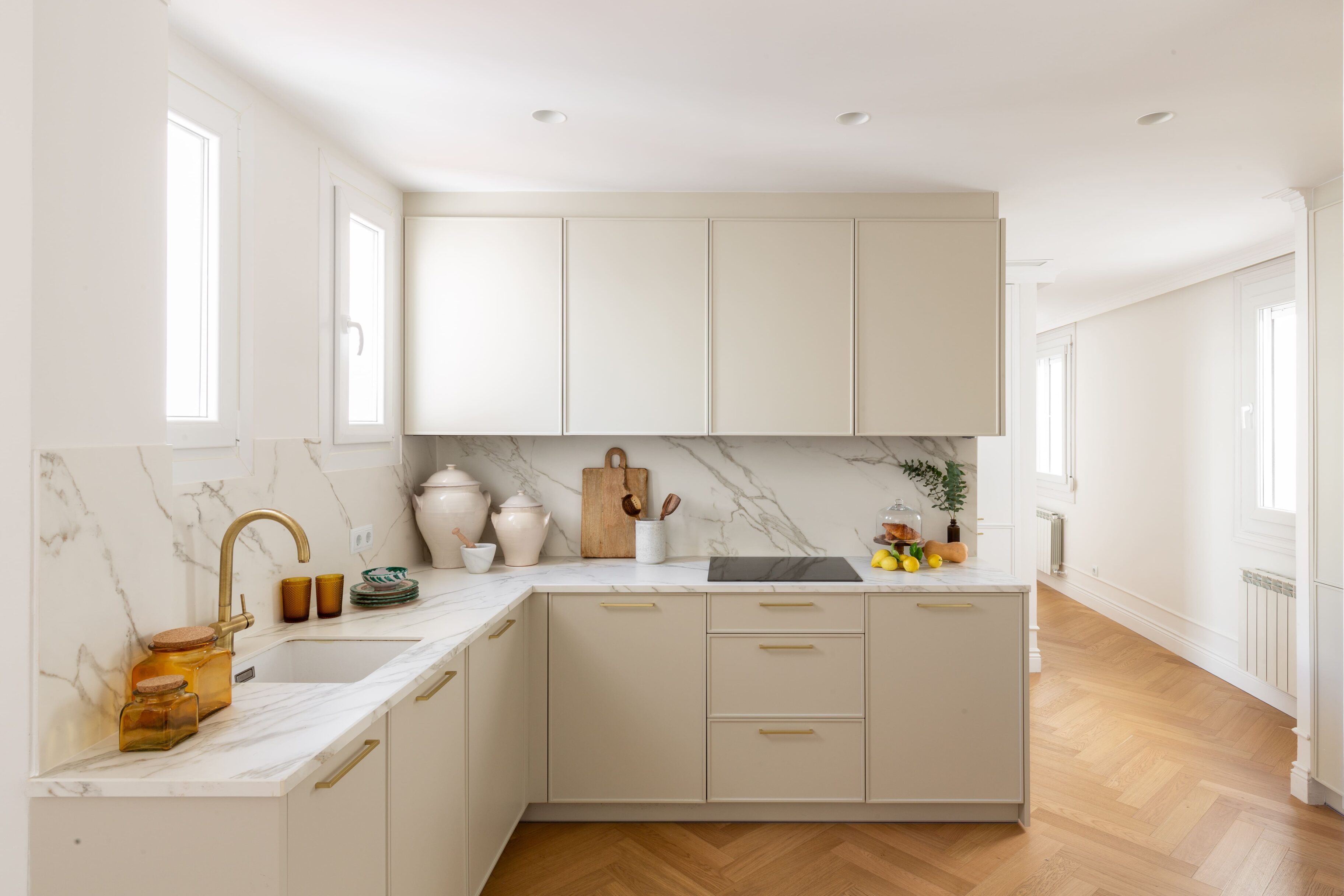 Cocina con muebles beige y salpicadero de mármol blanco