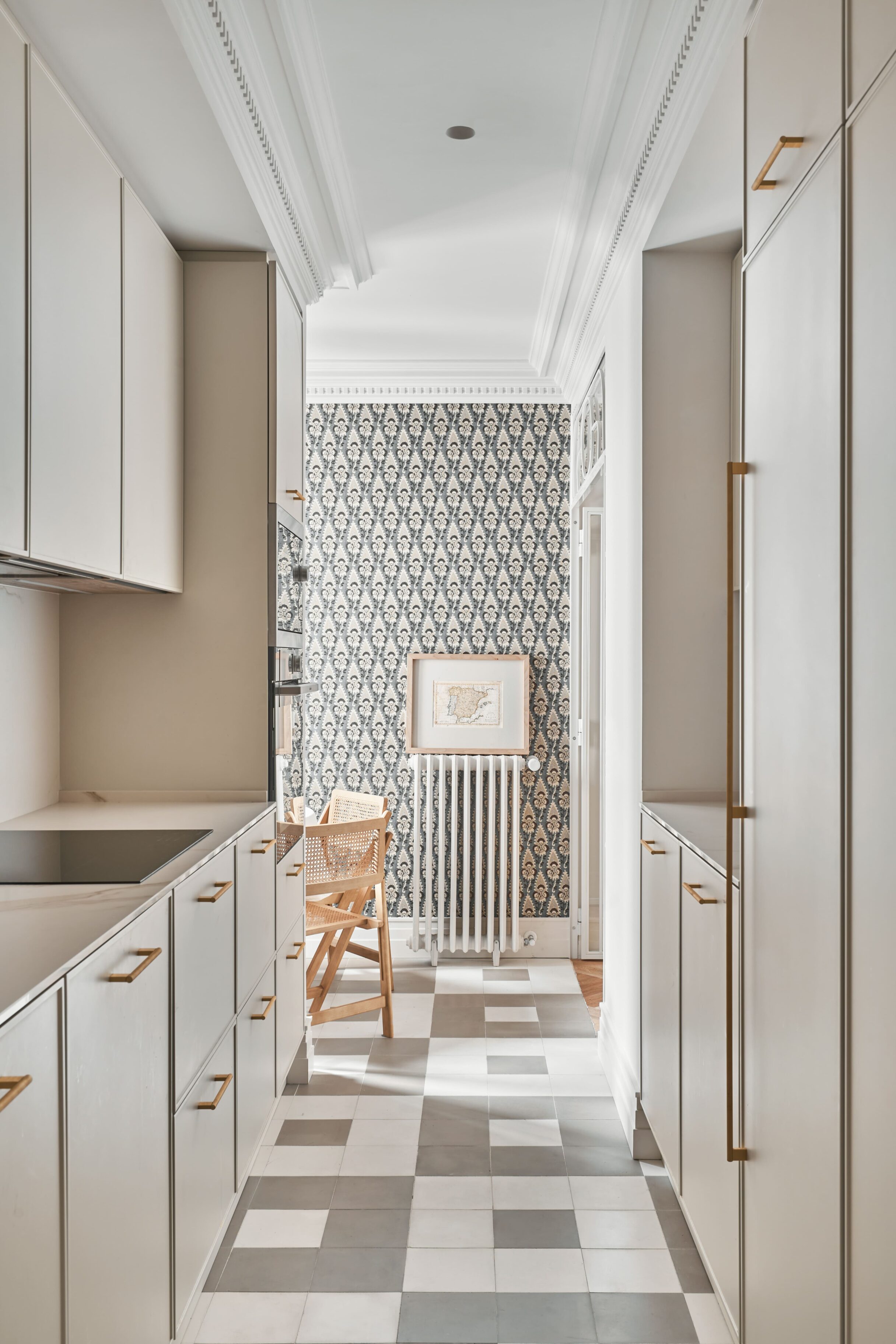 Cocina con armarios blancos, detalles en dorado y azulejos en el suelo