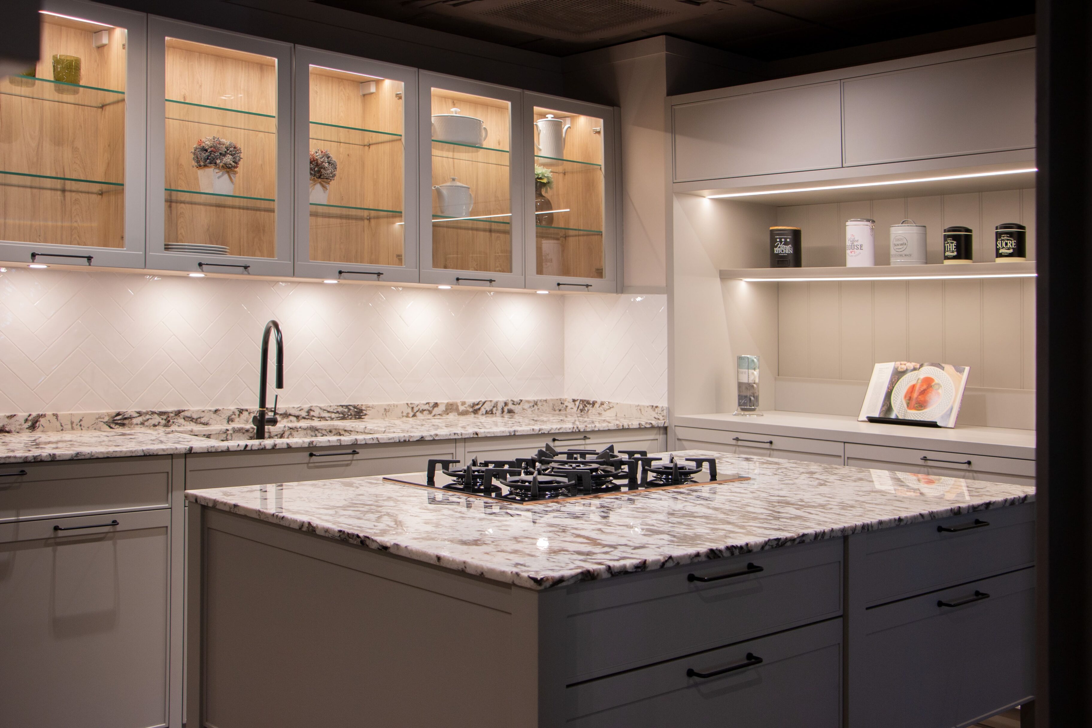 Cocina moderna con encimera de granito y estantes iluminados