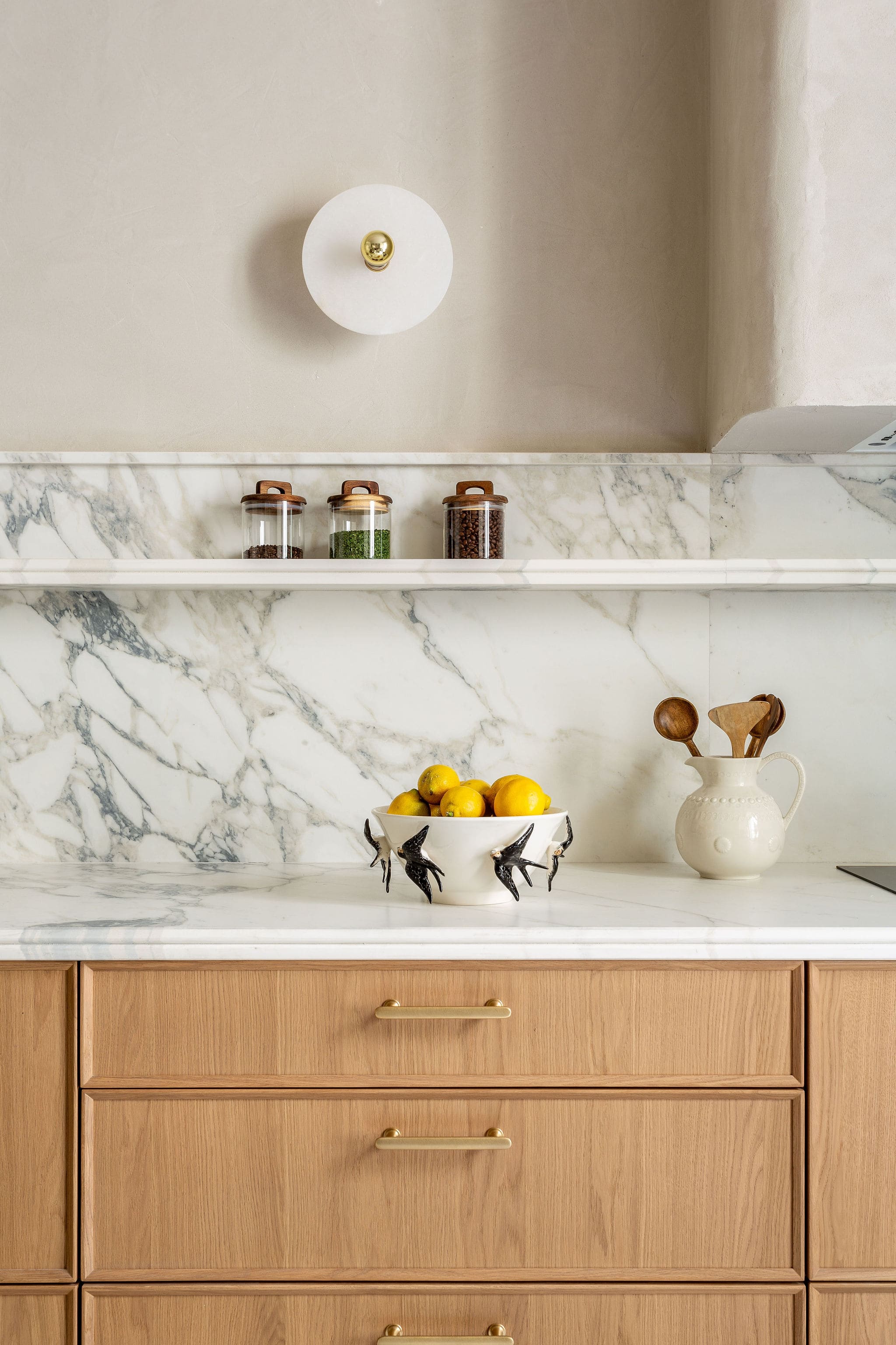 Encimera de mármol blanco con detalles en madera y decoración funcional en la cocina