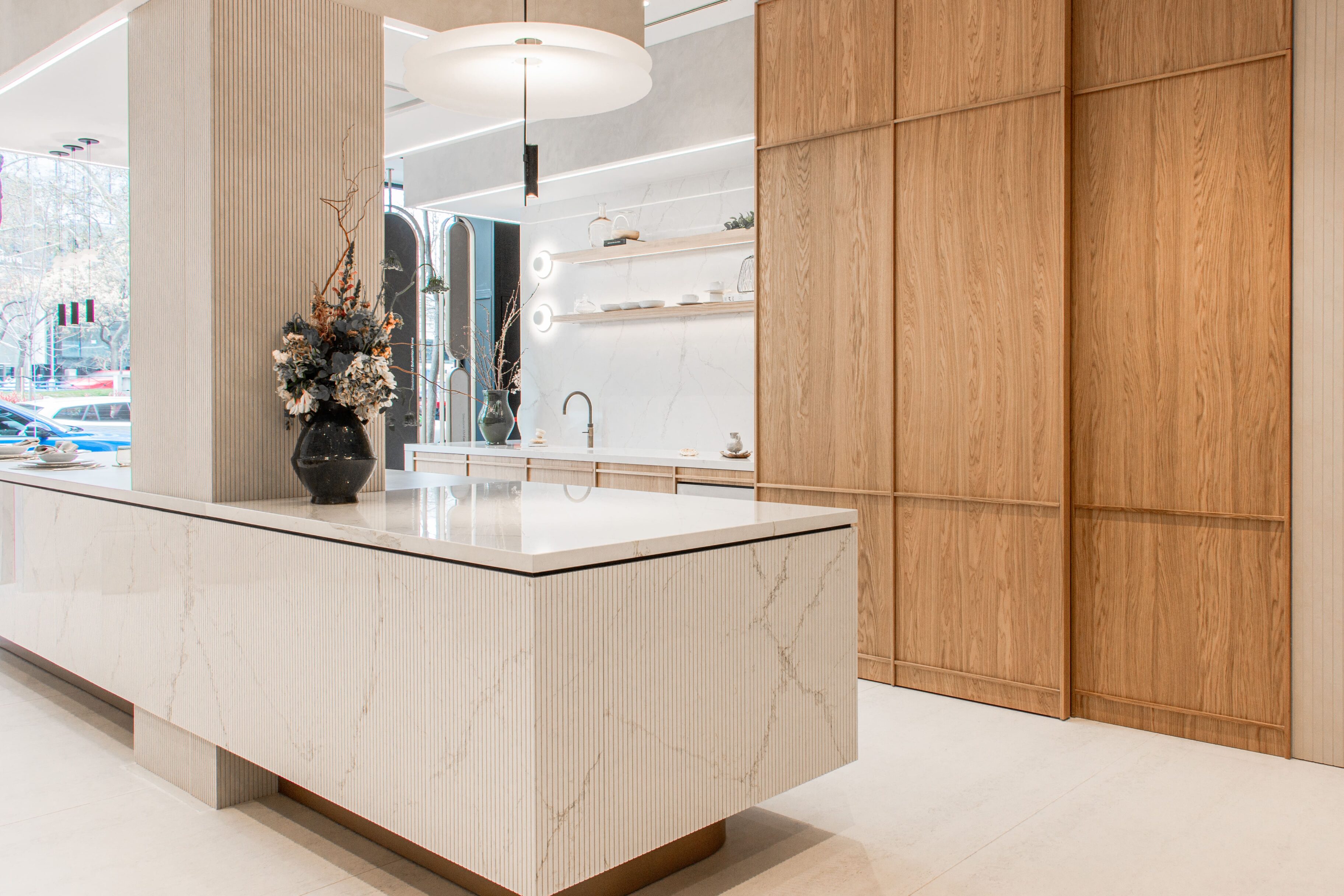 Isla de cocina con encimera blanca y detalles en madera clara