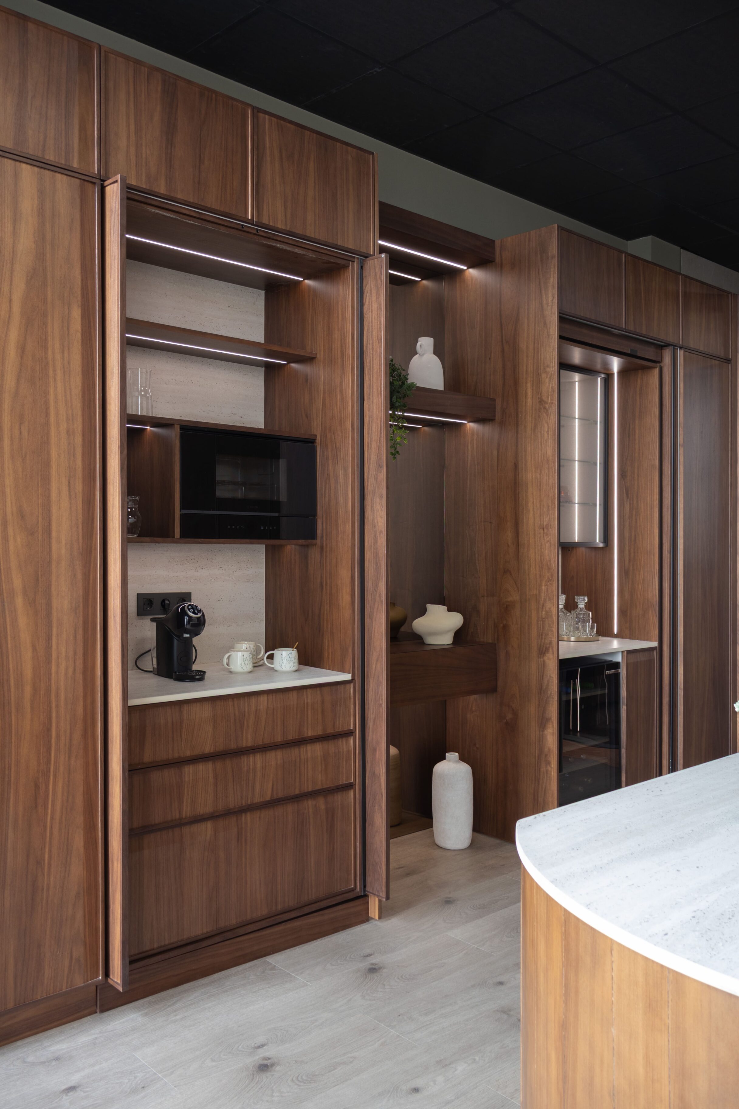 Cocina moderna con muebles de madera, encimera blanca y electrodomésticos integrados