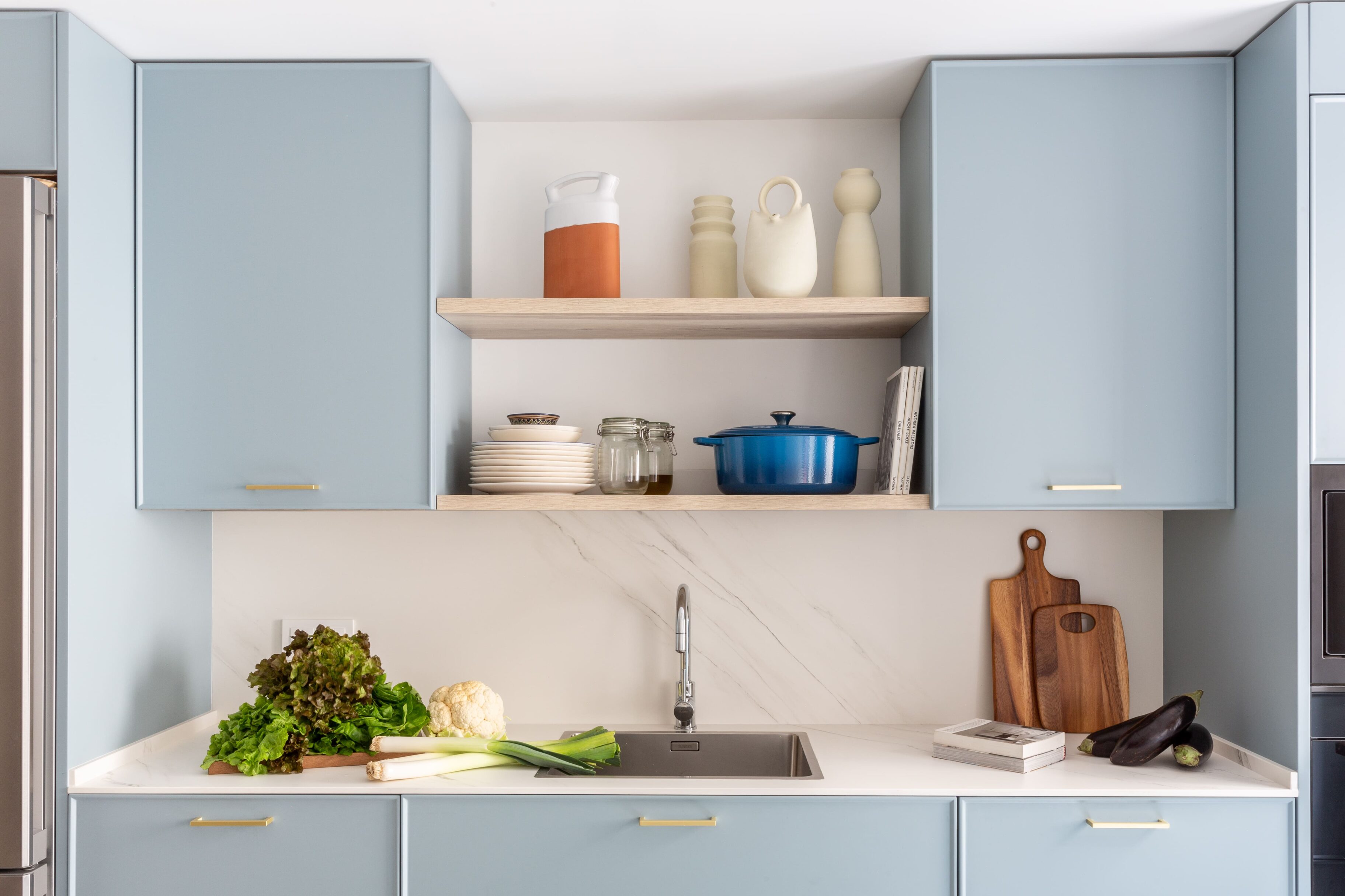 Cocina moderna con muebles bajos azules y estantería de madera