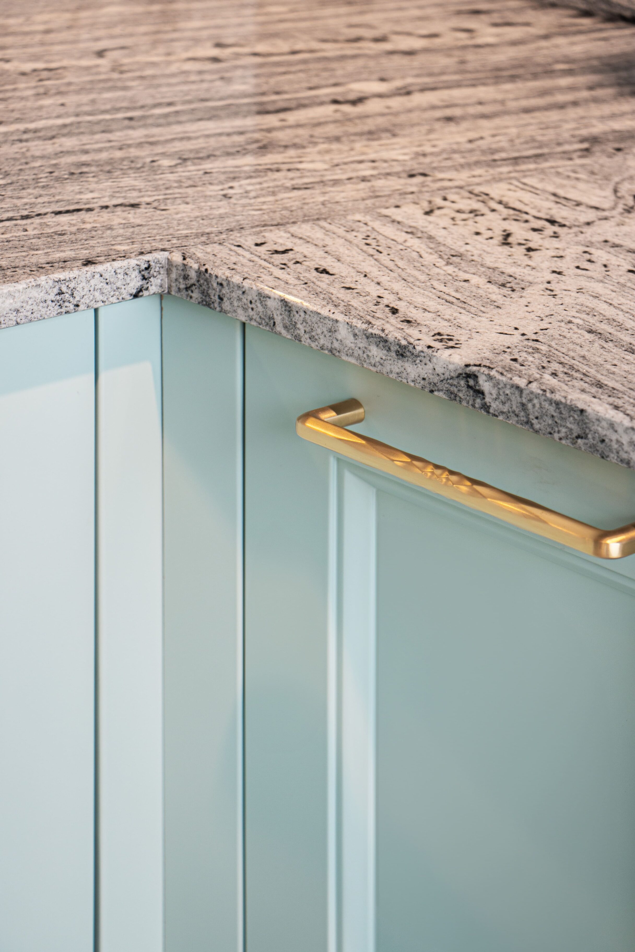 Mueble de cocina con acabado en color verde claro y encimera de granito gris