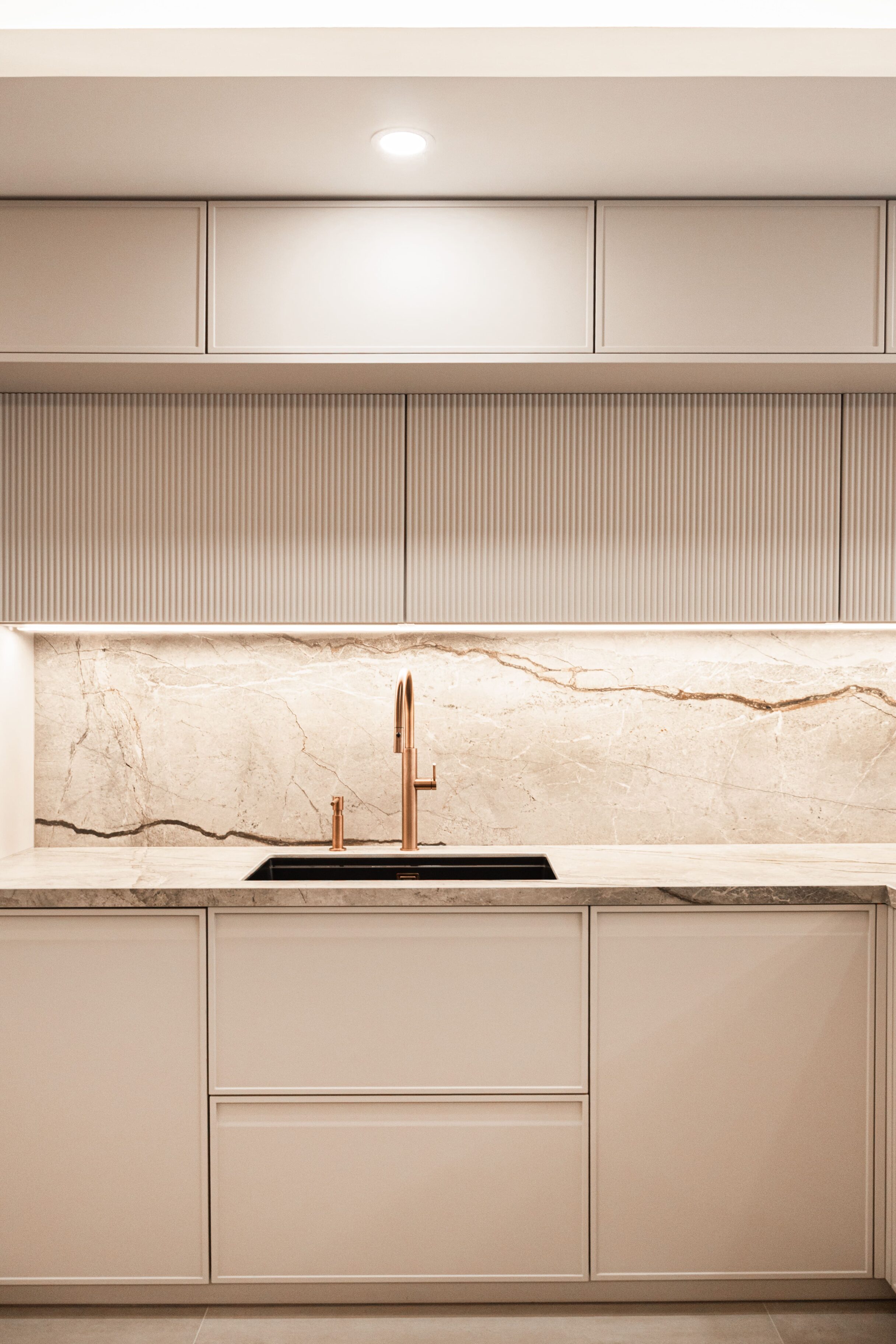 Cocina moderna con muebles en colores claros y encimera de mármol, grifería de color cobre