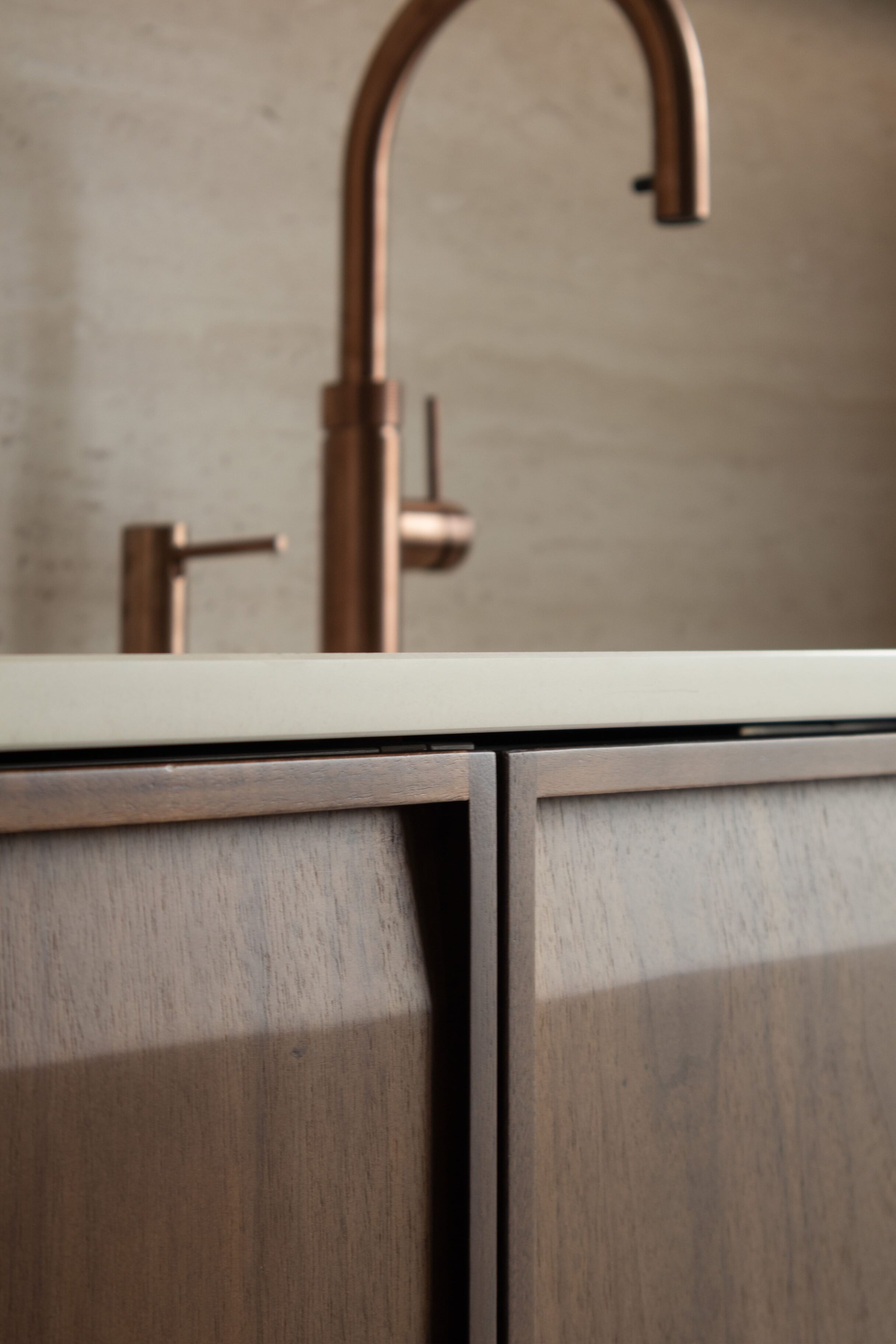 Grifo de cocina de acabado cobre sobre una encimera clara con muebles de madera