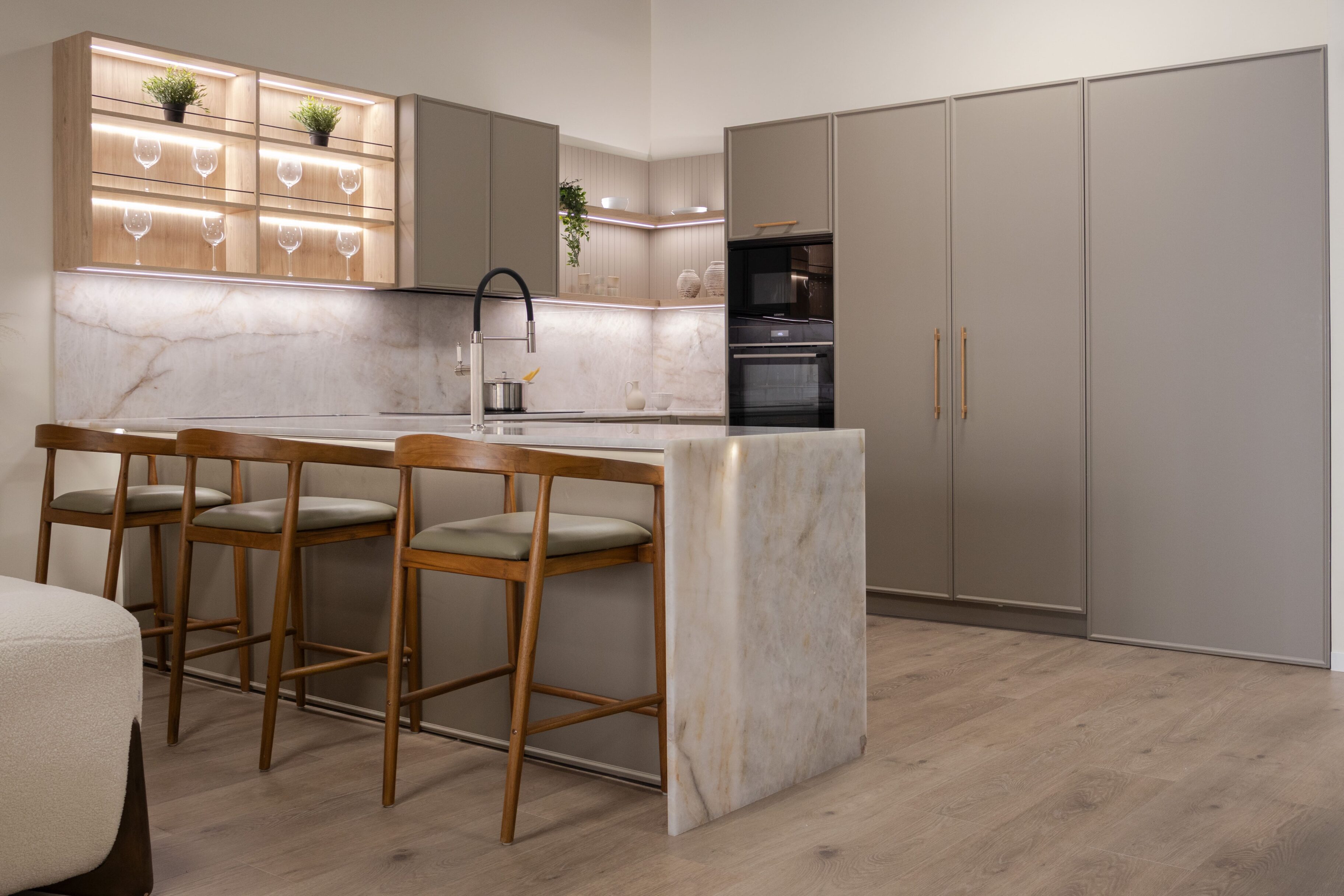 Cocina moderna con isla central, muebles gris claro y encimera de mármol