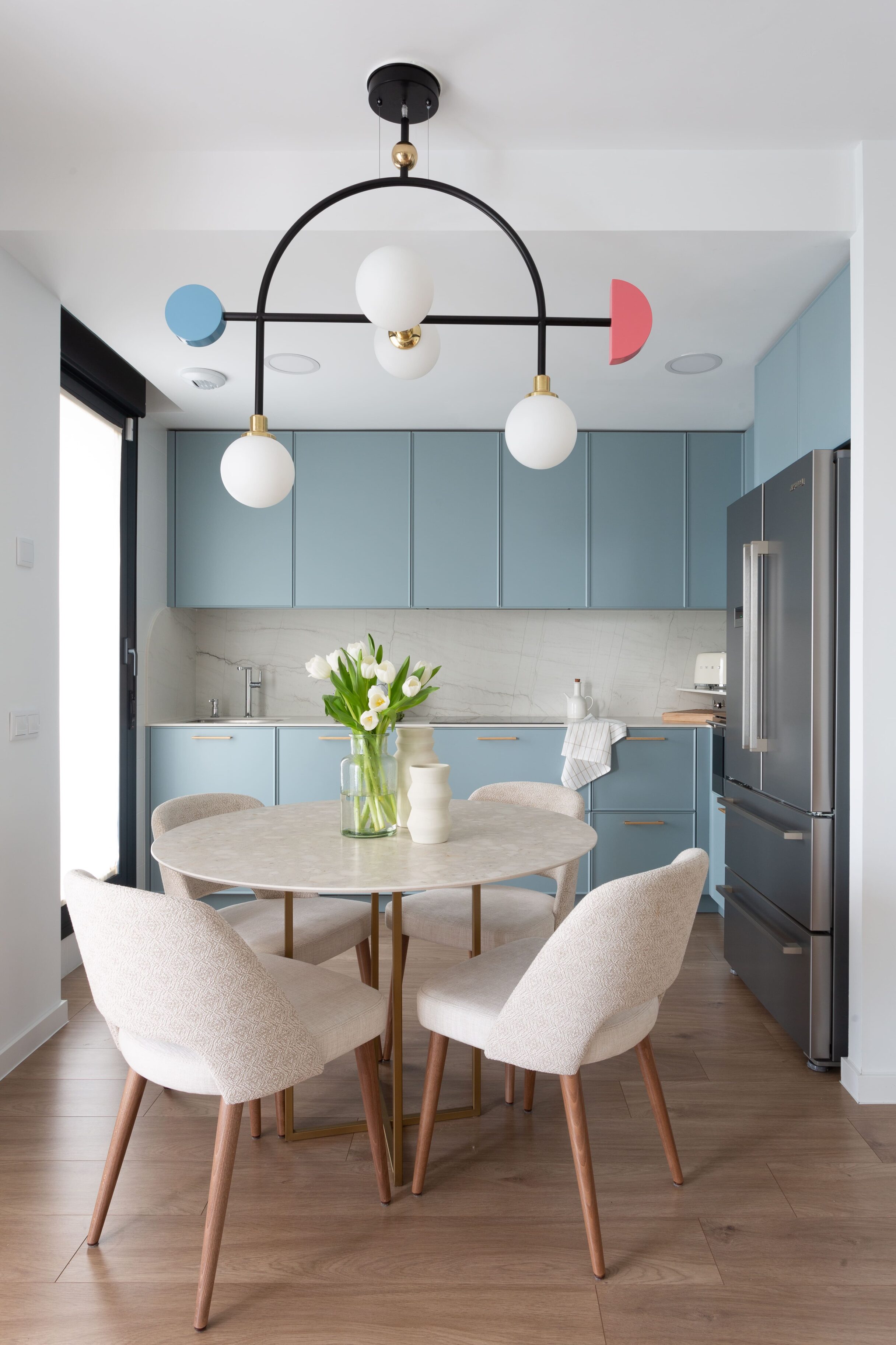 Lámpara de diseño moderno sobre mesa en cocina minimalista con muebles en tonos azul y madera