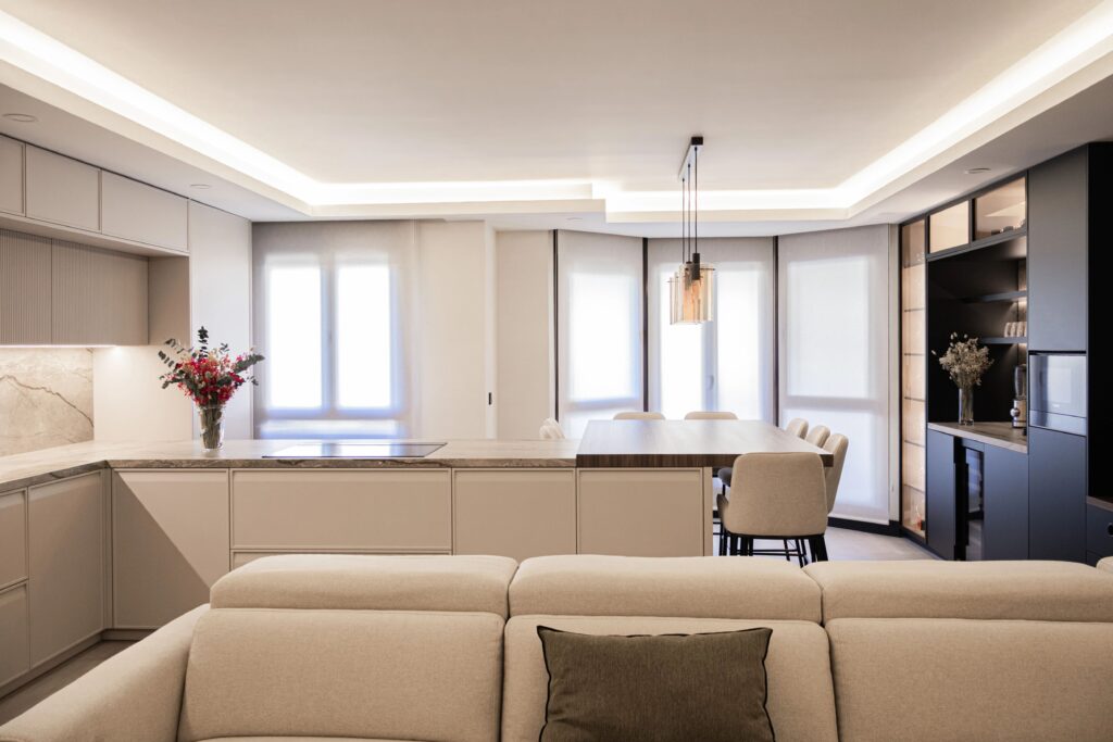 Cocina contemporánea con muebles beige y encimera de mármol, iluminación led y área de comedor