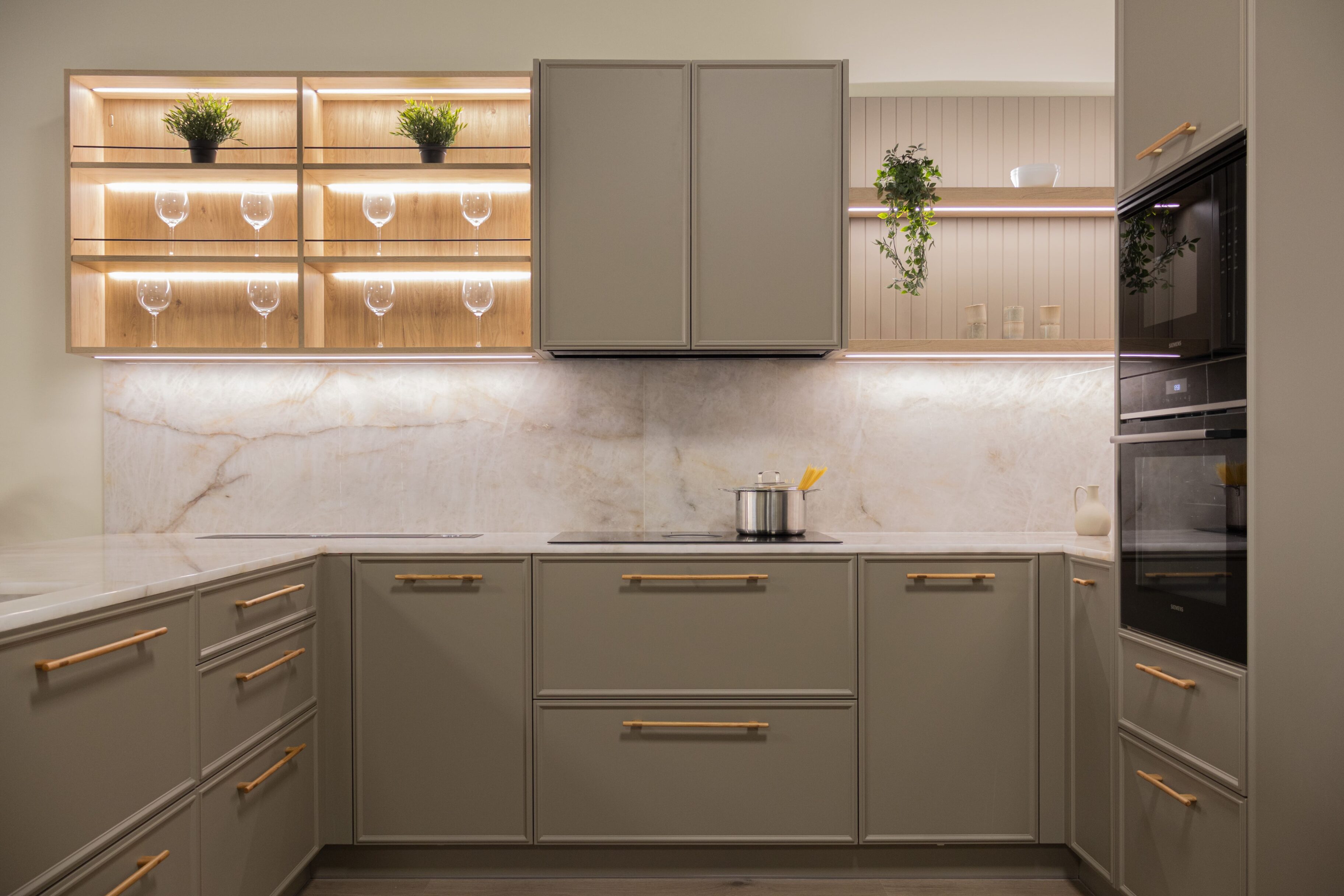 Cocina moderna con muebles de color gris, estantes iluminados y detalles en dorado