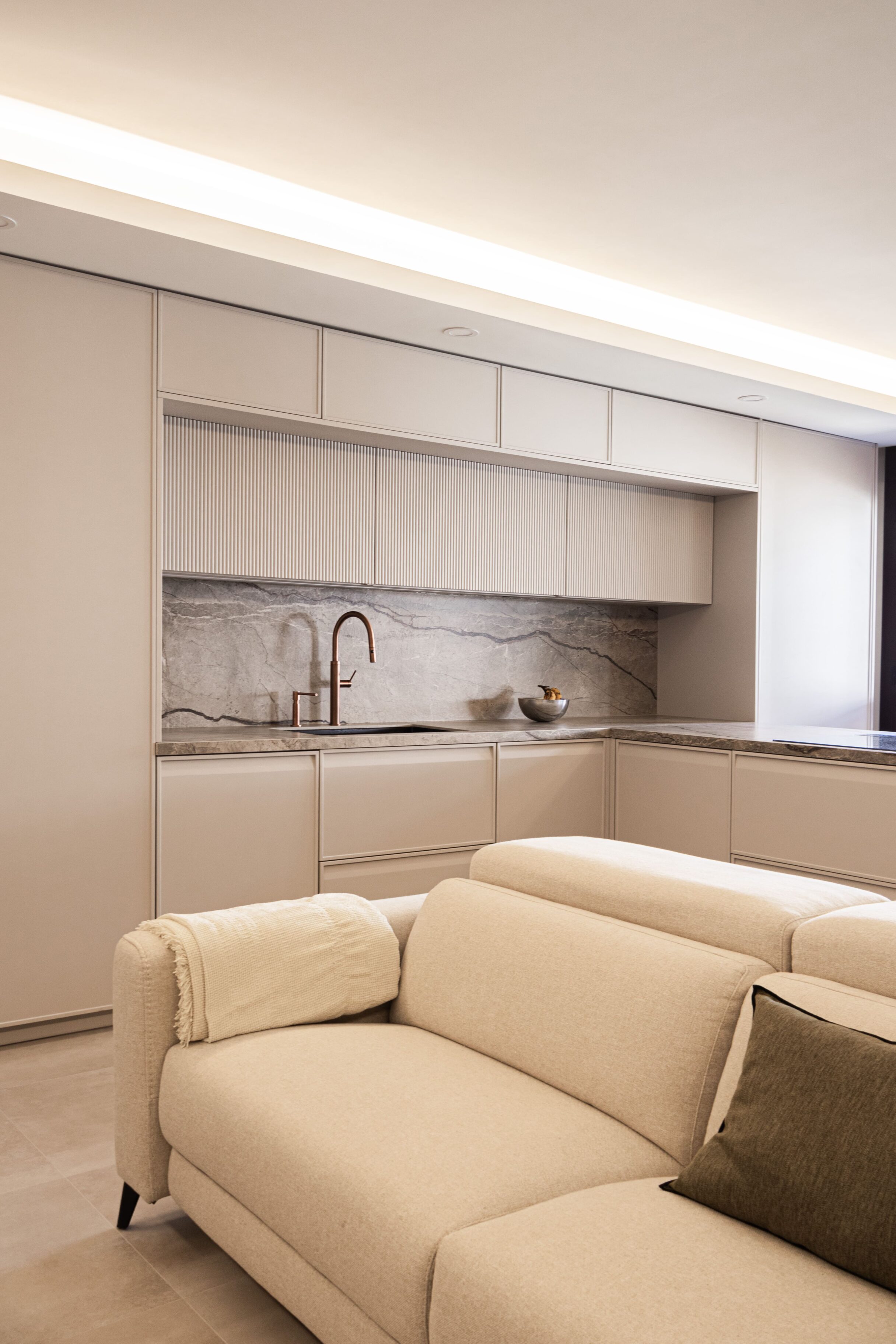 Cocina moderna con muebles beige y encimera de mármol.