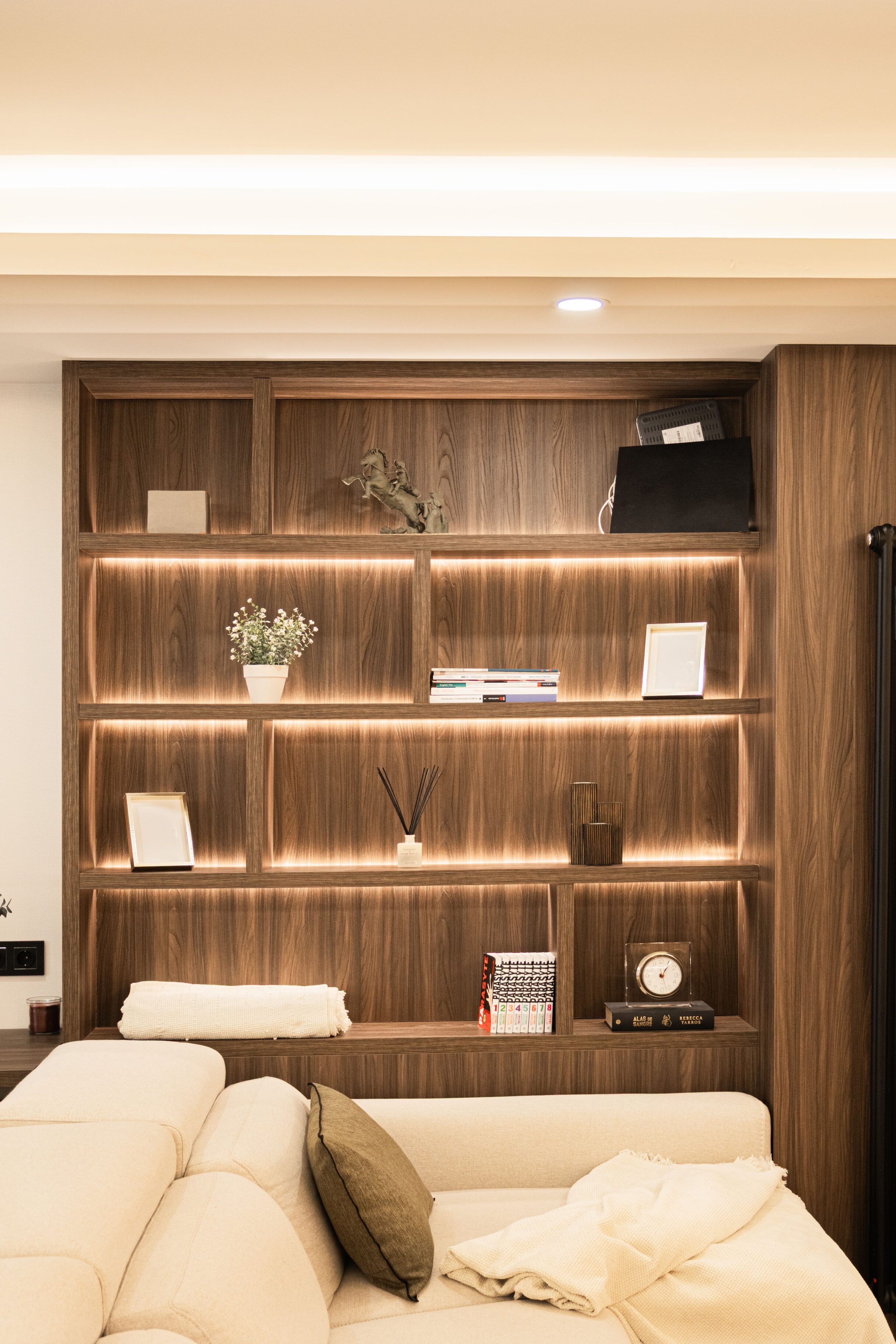 Estantería con iluminación LED en madera, decorada con libros y plantas.