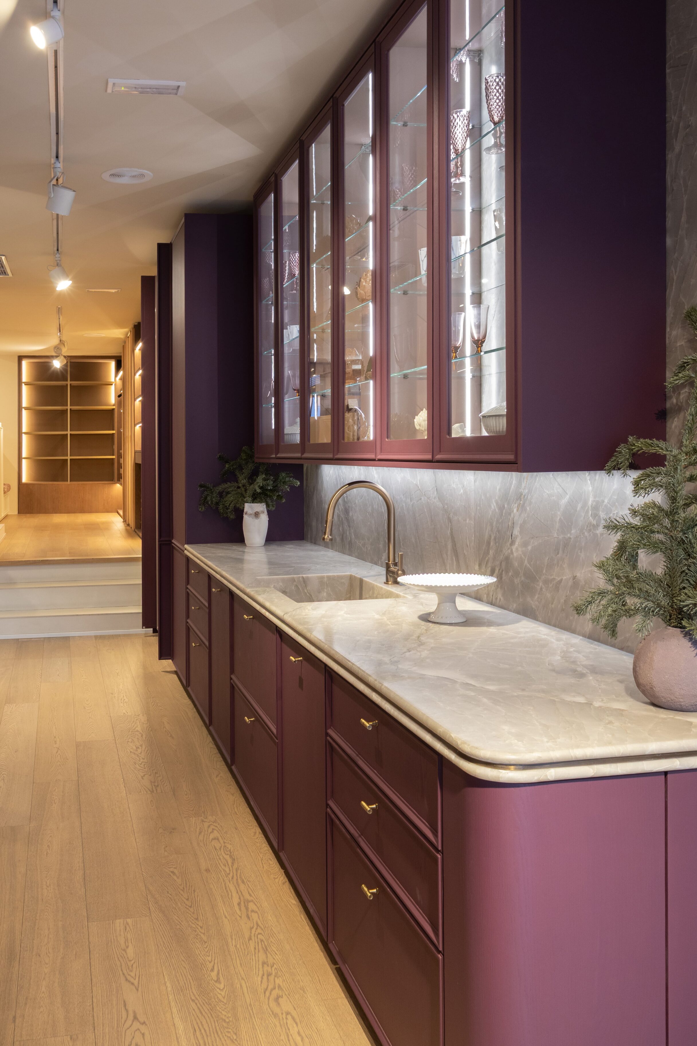 Muebles de cocina en color burdeos con encimera de mármol blanco y grifería dorada