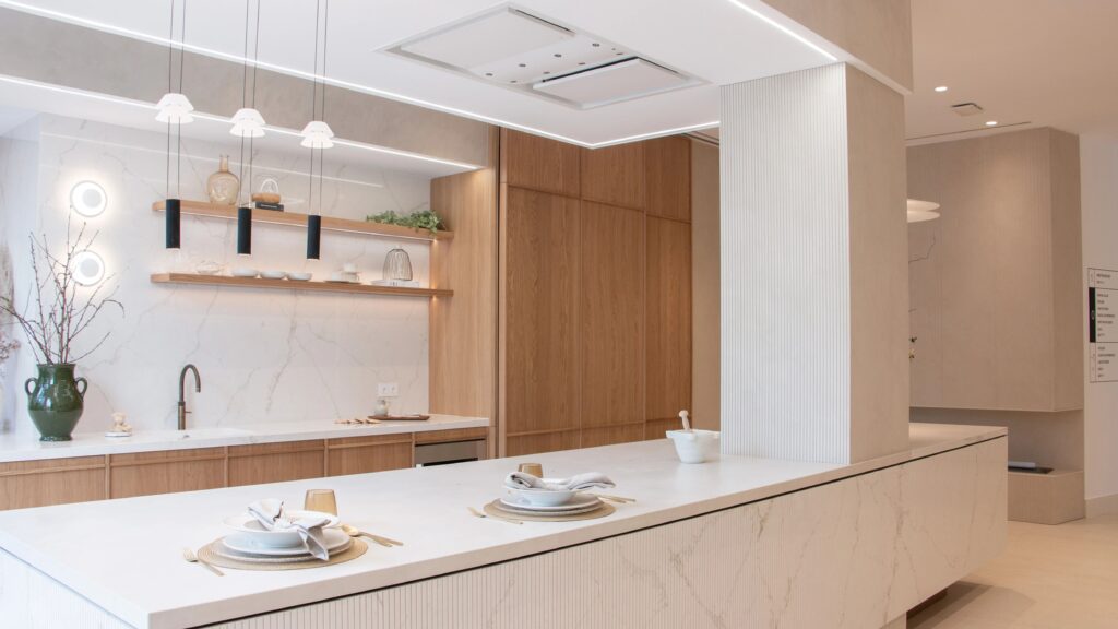 Cocina moderna con mesa de trabajo, estanterías de madera y detalles decorativos.