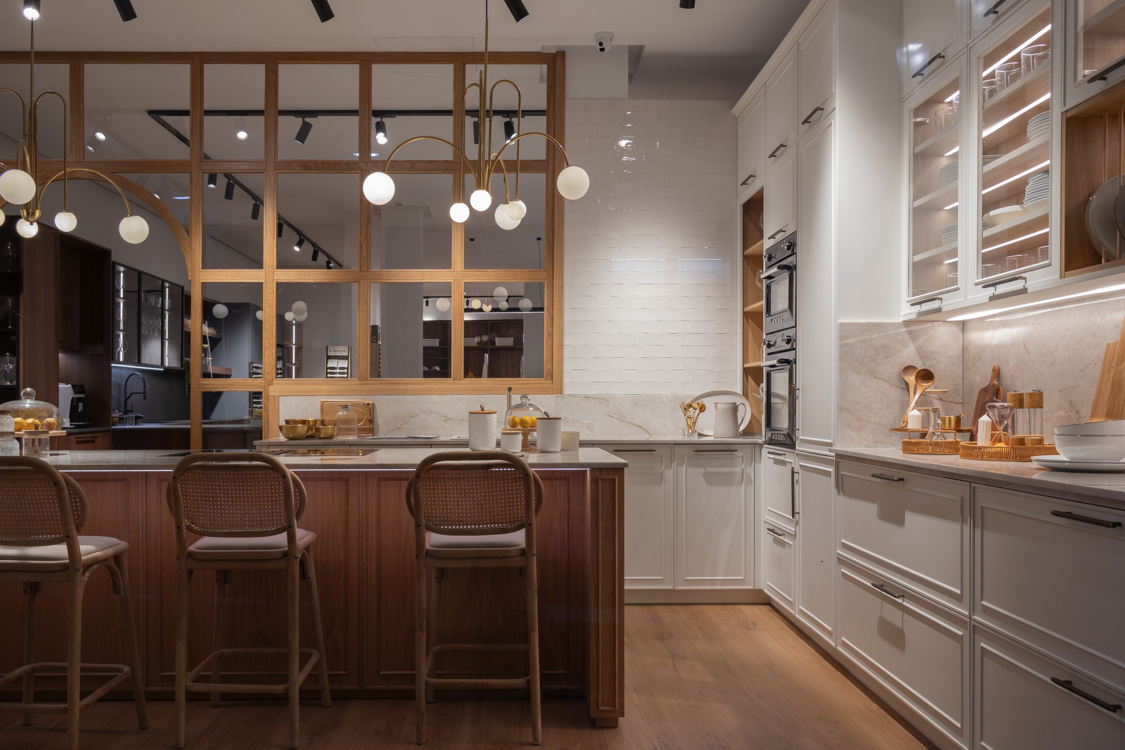 Cocina contemporánea con isla central, taburetes de madera y lámparas colgantes